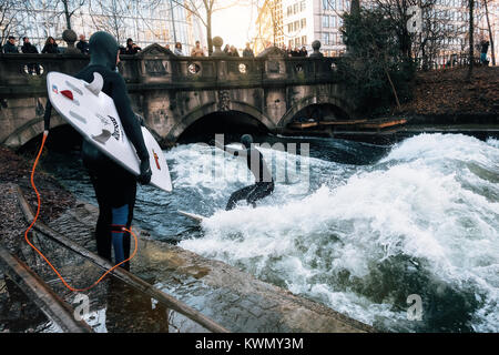 Der Surfer im Taucheranzug warten, die wiederum die künstliche Welle am Eisbach, gefährliche Wasser Isar Kanal am Englischen Garten zu fahren. Surfen Stockfoto