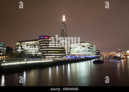 Skyline von London bei Nacht, einschließlich Shard und Rathaus, beleuchtet entlang der Themse. Stockfoto