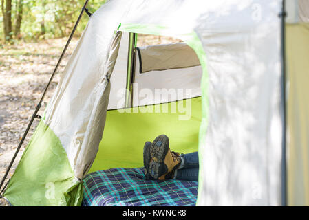 Frau Verlegung im Zelt mit Wanderschuhen auf Entspannung im Herbst Stockfoto