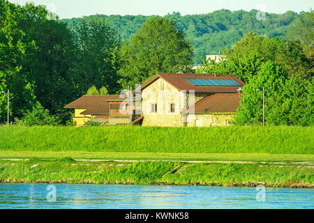 Blick auf die Donau Bank der Donaupark Linz Oberösterreich. Leuchtende grüne Farbe, goldenes Sonnenlicht Bergpanorama im Hintergrund. Sommer Spri Stockfoto