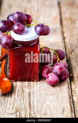 Jar mit Marmelade und Trauben auf einem hölzernen Hintergrund. Köstliches Dessert und frisches Obst. Stockfoto