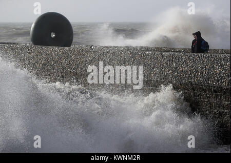 Ein paar stehen in der Nähe des "Flott" Skulptur von East Sussex Bildhauer Hamish Schwarz, während die Wellen auf den Strand in Brighton, Sussex, als frische Warnung vor starkem Wind hat für die Mehrheit der in England und Wales am Donnerstag herausgegeben worden. Stockfoto