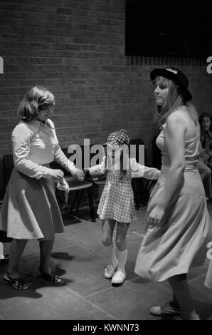 Jugendclub 1970s UK. Disco-Tanz im Timebridge Youth Club. Teenagerinnen tanzen Schwestern, die sich um ihre jüngere Schwester kümmern, die mit ihr zu Disco-Musik tanzt. Die Wells Fargo Disco. Chells, Stevenage, Hertfordshire. 1975 England HOMER SYKES. Stockfoto