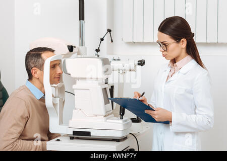 Seitenansicht des Patienten erste Augenuntersuchung in Spaltlampe in Klinik Stockfoto