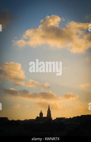 Mgarr, Gozo skyline Silhouette vom Meer mit Kirchen, Wolken und Sonnenuntergang Farben Stockfoto