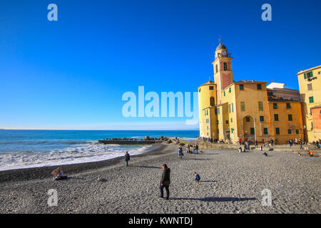 Camogli Italien - Menschen am Strand zu entspannen und die Basilika Santa Maria Assunta im Hintergrund Stockfoto