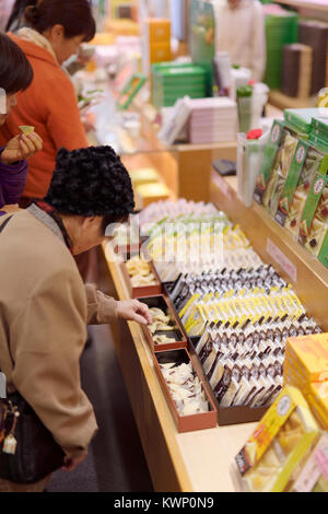 Menschen Probenahme japanischen Süßigkeiten, yatsuhashi Dreiecke an einem Souvenir Süßwaren store in Kyoto, Japan 2017 Stockfoto