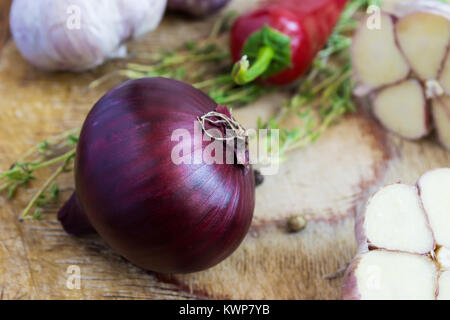 Rote Zwiebel und andere Gewürze auf einem alten Holztisch. Stockfoto