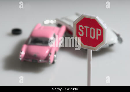 Zwei retro Spielzeug Autos bei einem Unfall unter einem Stoppschild. Stockfoto