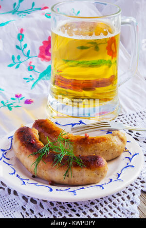 Bier und gebratene Würstchen auf einem weißen Hintergrund. Selektiver Fokus Stockfoto