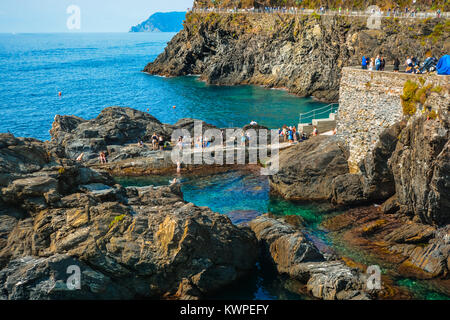 Touristen und Einheimische genießen Sie das Schwimmen im seichten Meer Wasser von Manarola Italien an einem sonnigen Tag an der Küste von Cinque Terre Italien Stockfoto