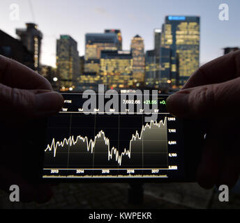 Eine Person, die Aussicht auf ein Iphone, mit der Londoner Canary Wharf im Hintergrund. Stockfoto