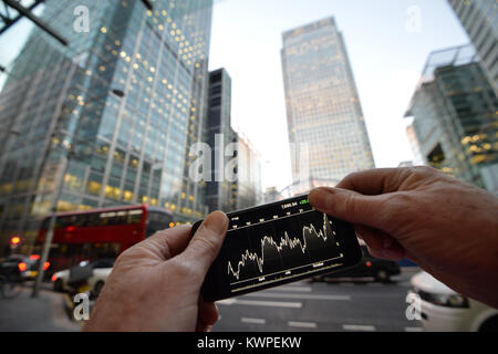 Eine Person, die Aussicht auf ein Iphone, mit der Londoner Canary Wharf im Hintergrund. Stockfoto