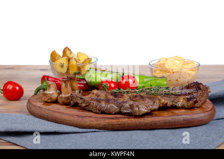 Detaillierte Ansicht von lecker lecker Gegrilltes Steak auf Holzplatte mit Kartoffel, Tomate und roter Pfeffer serviert. Stockfoto