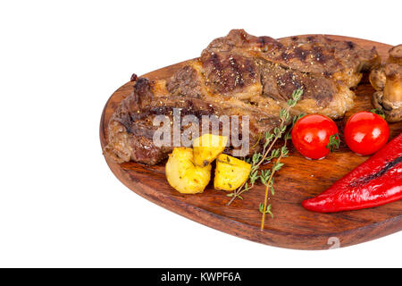 Detaillierte Ansicht von lecker lecker Gegrilltes Steak auf Holzplatte mit Kartoffel, Tomate und Paprika diente, auf weißem Hintergrund. Stockfoto