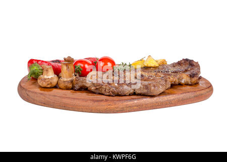 Detaillierte Ansicht von lecker lecker Gegrilltes Steak auf Holzplatte mit Kartoffel, Tomate und Paprika diente, auf weißem Hintergrund. Stockfoto
