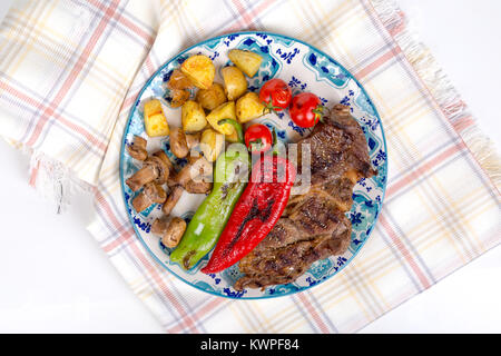 Detaillierte Ansicht von lecker lecker Gegrilltes Steak auf Holzplatte mit Kartoffel, Tomate und roter Pfeffer serviert. Stockfoto