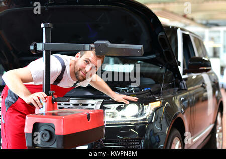 Autowerkstatt - Arbeitnehmer überprüft und passt die Leuchtweite der Beleuchtung ist ein Auto Stockfoto
