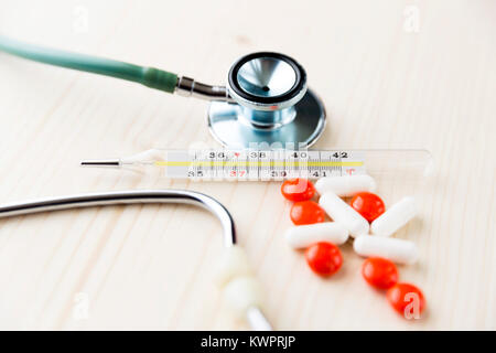 Stethoskop, Pillen und Thermometer auf Holztisch. Medizin und Behandlung Konzept Stockfoto