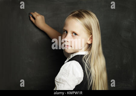 Schulmädchen zieht mit Kreide auf Tafel Stockfoto