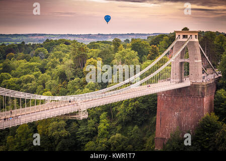 Clifton Suspension Bridge an einem bewölkten Tag mit einem Heißluftballon im Hintergrund, Bristol, England Stockfoto