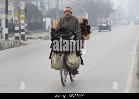 Srinagar, Indisch kontrollierten Teil Kaschmirs. 5 Jan, 2018. Ein Anbieter verkauft Kleidung auf seinem Fahrrad an einem kalten Morgen in Srinagar, Sommer Hauptstadt von Indien kontrollierten Teil Kaschmirs, Jan. 5, 2018. Credit: Javed Dar/Xinhua/Alamy leben Nachrichten Stockfoto