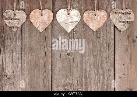 Rustikale Birkenrinde herzen Ornamente gegen einen Vintage Holz- Hintergrund hängenden Stockfoto