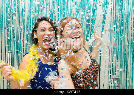 Zwei Frauen, eine Kaukasische und eine orientalische, Feiern Karneval in Brasilien. Viel Freude mit dem Regen aus Konfetti. Die Mädchen sind euphorisch. Stockfoto