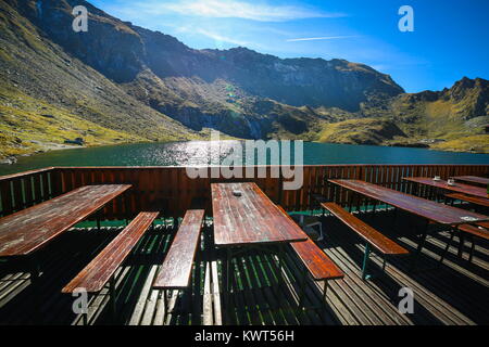 Picknick-tische am Ufer des Balea See mit Fagaras Gebirge im Hintergrund in Sibiu, Rumänien Stockfoto