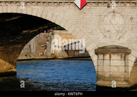 Anzeigen unter der Petit Pont auf der Pont au Double und Leute sitzen auf der Treppe hinunter zur Seine, Paris, Frankreich Stockfoto