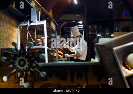 Lvov, Ukraine - 22.01.2017: Lemberg Schokolade Workshop. Konditor in weißen Hut gießen Schokolade für die Herstellung von Schokolade Stockfoto