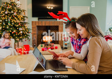 Kleines Mädchen ist und das Schreiben von Weihnachtskarten mit ihrer Mutter am Esstisch in Ihrem Haus. Stockfoto