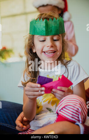 Gerne kleine Mädchen spielen mit allen Hüte aus der Christmas Crackers in Ihrem Haus zur Weihnachtszeit. Stockfoto