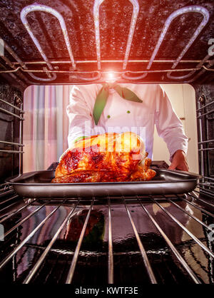 Chefkoch gebratenes Huhn in den Ofen, Blick aus dem Inneren des Ofens. Kochen in den Ofen. Stockfoto