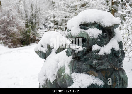 Chinese Foo Dog Bronzestatue und Winter Bäume im Schnee im Dezember bei Batsford Arboretum, Cotswolds, Moreton-in-Marsh, Gloucestershire, England Stockfoto