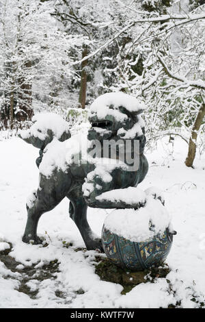 Chinese Foo Dog Bronzestatue und Winter Bäume im Schnee im Dezember bei Batsford Arboretum, Cotswolds, Moreton-in-Marsh, Gloucestershire, England Stockfoto