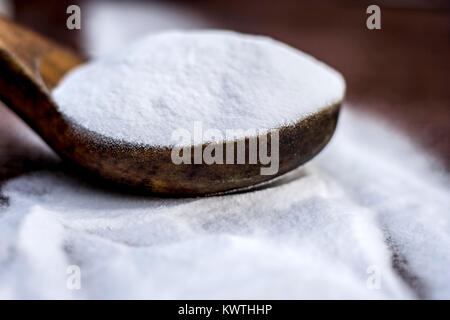 Natron oder Natriumhydrogencarbonat in eine hölzerne Schaufel auf den braunen Holz- Oberfläche. Stockfoto