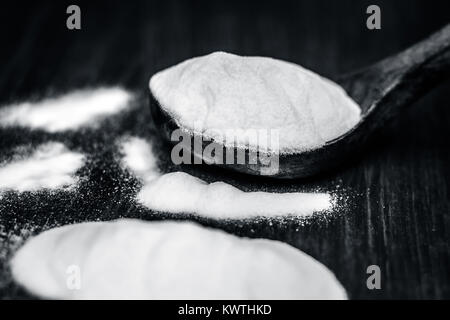 Natron oder Natriumhydrogencarbonat in eine hölzerne Schaufel auf den braunen Holz- Oberfläche. Stockfoto
