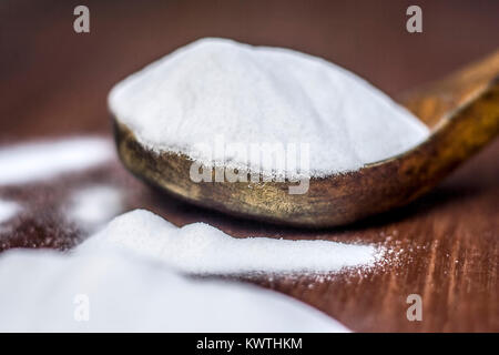 Natron oder Natriumhydrogencarbonat in eine hölzerne Schaufel auf den braunen Holz- Oberfläche. Stockfoto