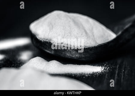 Natron oder Natriumhydrogencarbonat in eine hölzerne Schaufel auf den braunen Holz- Oberfläche. Stockfoto