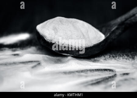 Natron oder Natriumhydrogencarbonat in eine hölzerne Schaufel auf den braunen Holz- Oberfläche. Stockfoto