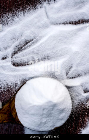 Natron oder Natriumhydrogencarbonat in eine hölzerne Schaufel auf den braunen Holz- Oberfläche. Stockfoto