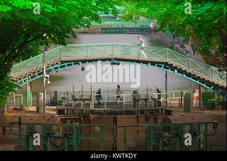 Paris Canal Saint-Martin, ein Mann joggt über eine eiserne Brücke überspannt den Kanal Saint-Martin im 10. Arrondissement von Paris, Frankreich. Stockfoto