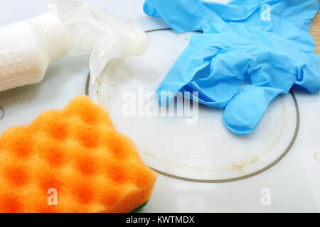 Reinigung verschmutzter elektrischen Herd. In der Nähe von blauen Handschuh, Staub und schwamm auf dem weißen Herd. Stockfoto