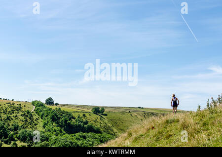 Eine Frau Wanderungen die üppigen Peak District Landschaft mit dem Tal mit Blick auf die Mensal Trail, England