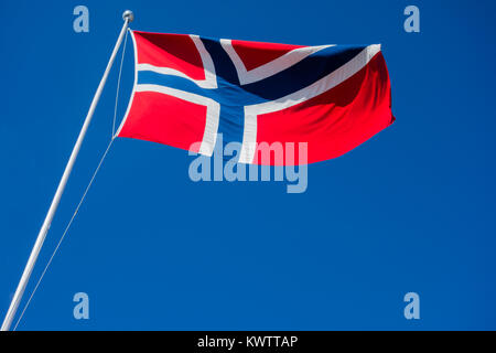 Flagge Norwegen auf Pole flattern im Wind gegen den klaren blauen Himmel. Stockfoto