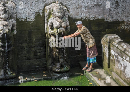 Balinesischen Mann in traditioneller Kleidung rituell die Hände waschen bei Goa Gajah Badetempel, Ubud, Bali, Indonesien Stockfoto