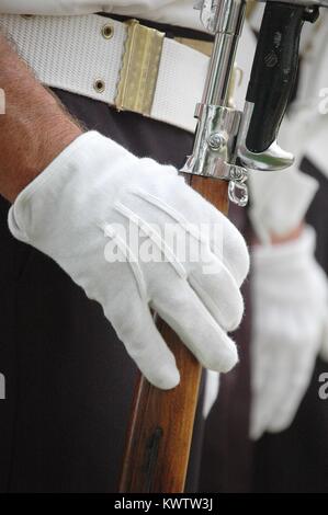 Mit weißen Handschuhen bedeckt mit der rechten Hand hält auf ein Gewehr beim Stehen in Uniform an Aufmerksamkeit. Nahaufnahme der Hand und Gürtel. Stockfoto