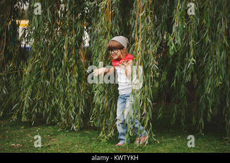 Wenig glücklich Mädchen versteckt sich in der Willow Laub Stockfoto