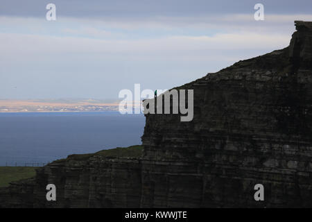 Einsame Person, die auf Klippe, die Klippen von Moher, die wilden Atlantik weg, County Clare, Irland Stockfoto